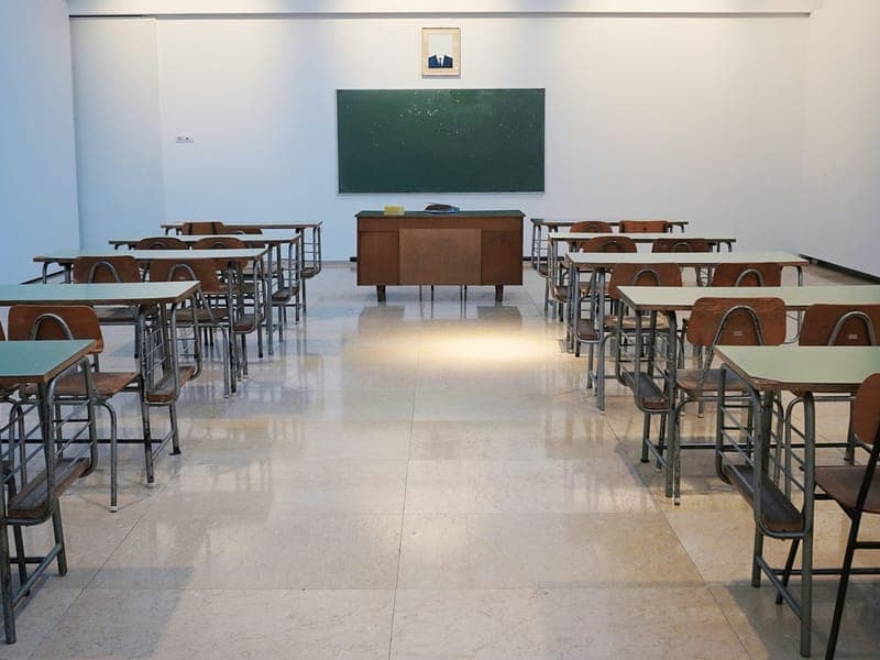 Aula vacía con pupitres ordenados frente al pizarrón
