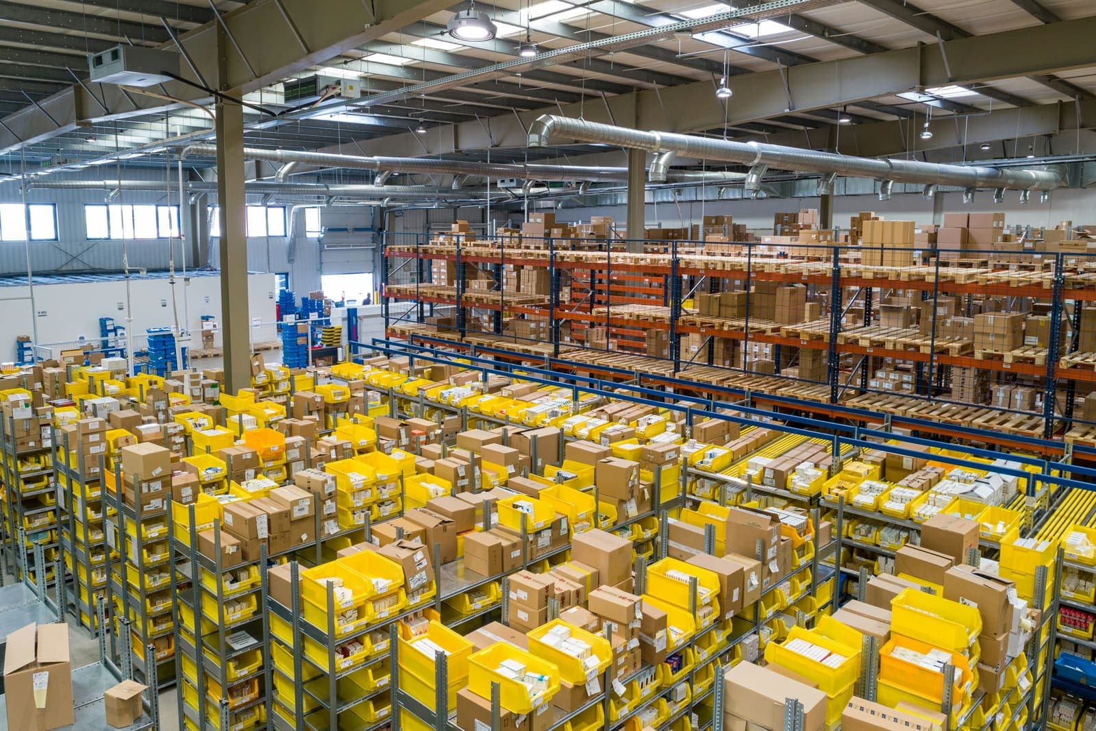 Depósito con estanterías cargadas de cajas y contenedores de paquetería